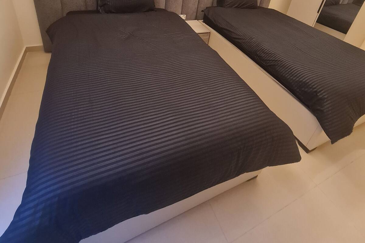 Una camera da letto moderna con un letto grande, un letto più piccolo e uno specchio.