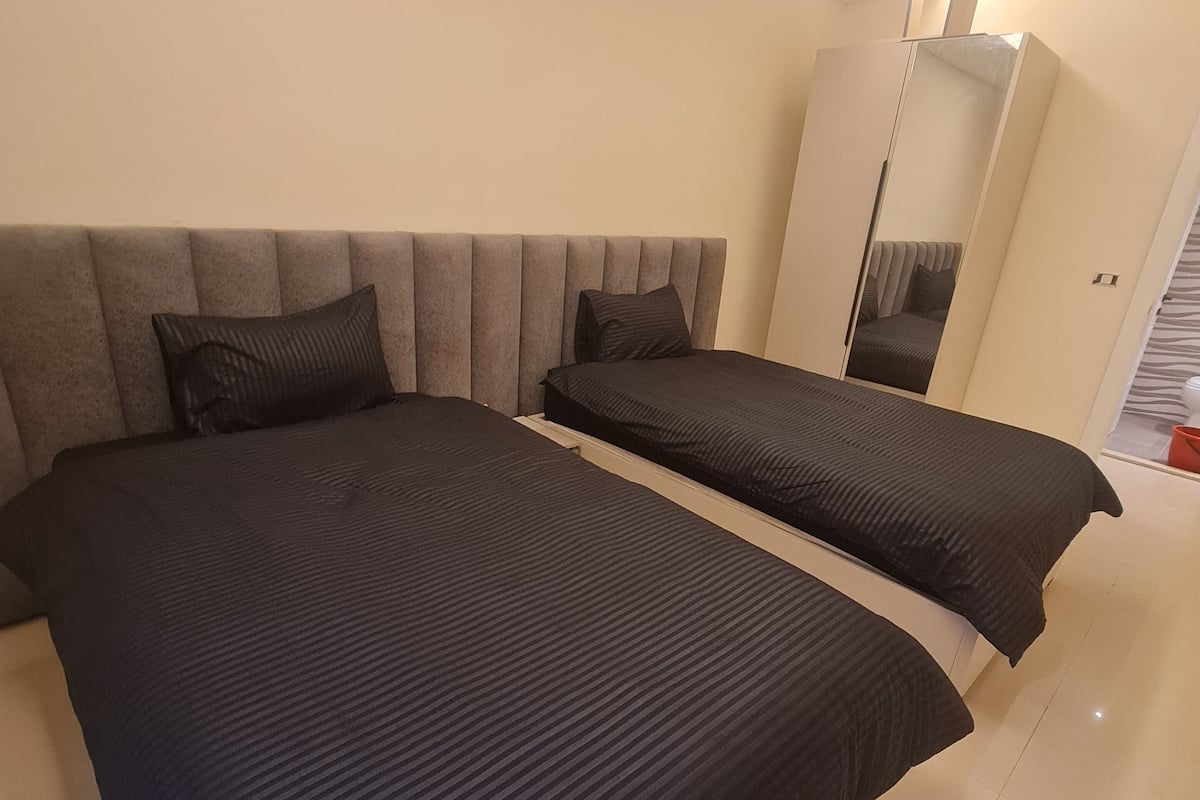 Camera da letto con due letti, un grande specchio e un armadio.