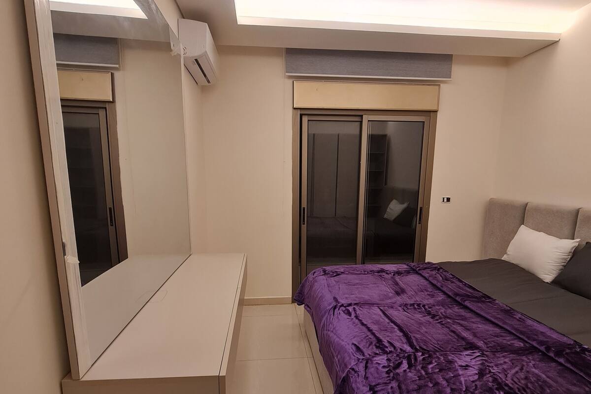 Una camera da letto con un letto, uno specchio grande, una porta scorrevole e una luce a soffitto.