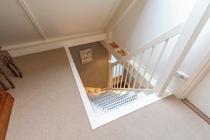 A staircase with a white railing and a textured carpet.