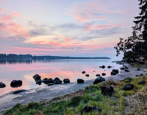 Um lago calmo com margem rochosa e árvores ao fundo.