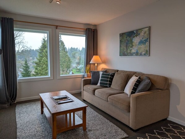 A living room with a sofa, a coffee table, a lamp, and a painting on the wall.