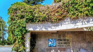 Entree van een resort met een bord voor Pacific Shores Resort & Spa, omringd door groen.
