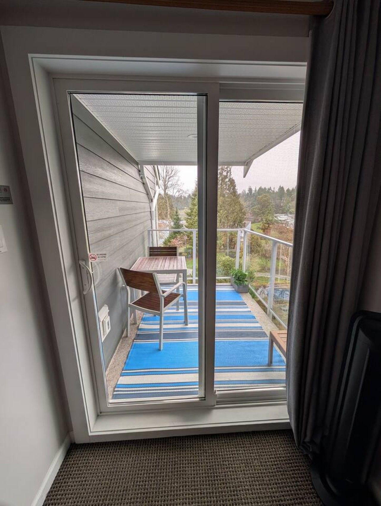 Ein Zimmer mit einer Schiebetür und Zugang zu einem Balkon mit Tisch und Stühlen.