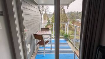 Ein Zimmer mit einer Schiebetür und Zugang zu einem Balkon mit Tisch und Stühlen.