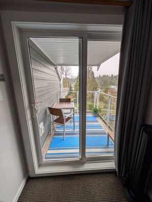 A room with a sliding glass door leading to an outdoor balcony with a table and chairs.