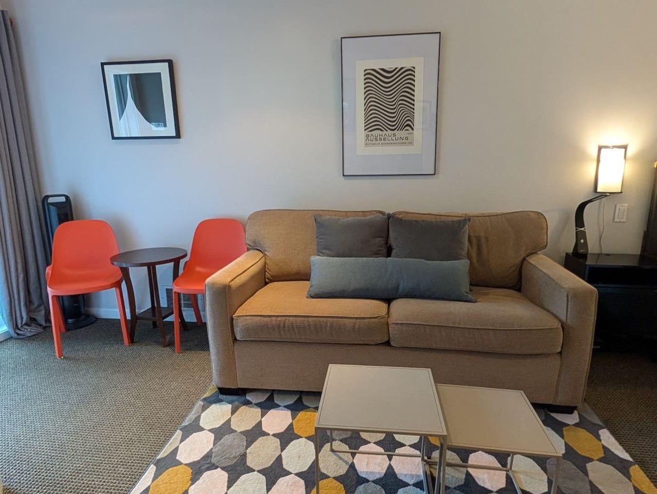 Ein Wohnzimmer mit einer Couch, zwei roten Sesseln, einem kleinen Tisch und einem gemusterten Teppich.