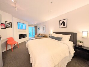 A hotel room with a bed, a desk, a chair, a TV, and a window.