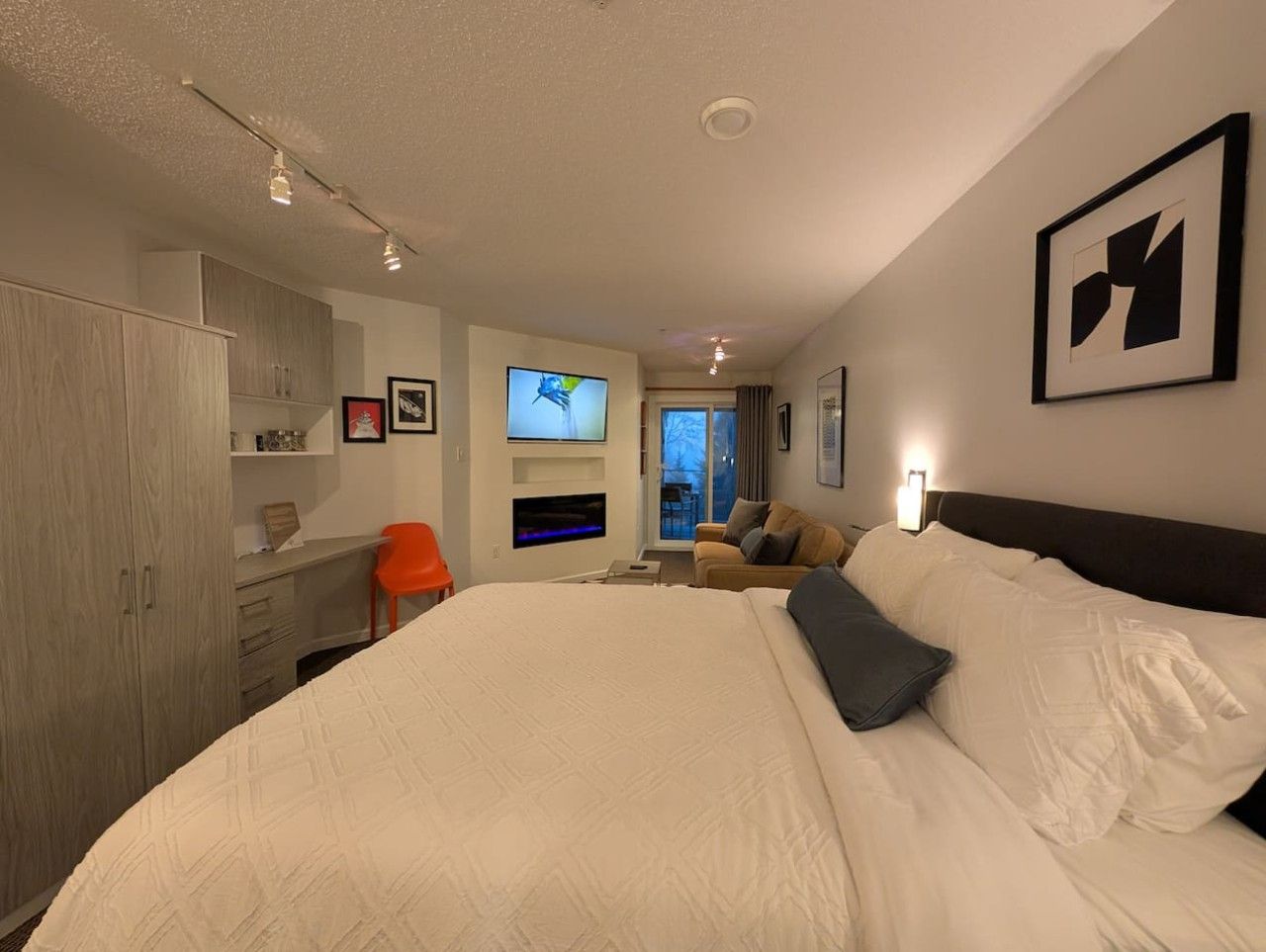 Ein Hotelzimmer mit einem großen Bett, einem Schreibtisch, einem Fernseher und Blick ins Freie.
