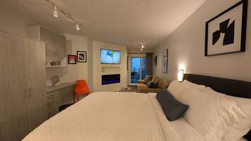 Ein Hotelzimmer mit einem großen Bett, einem Schreibtisch, einem Fernseher und Blick ins Freie.