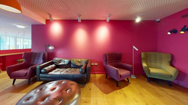 A modern living room with a red wall, a leather sofa, two armchairs, and a floor lamp. - For Student Only Cosy Studios in the Central London - Campus Accommodation (London)