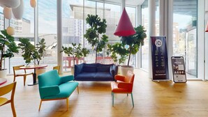Een moderne binnenruimte met een blauwe bank, oranje stoelen en een rode hanglamp.