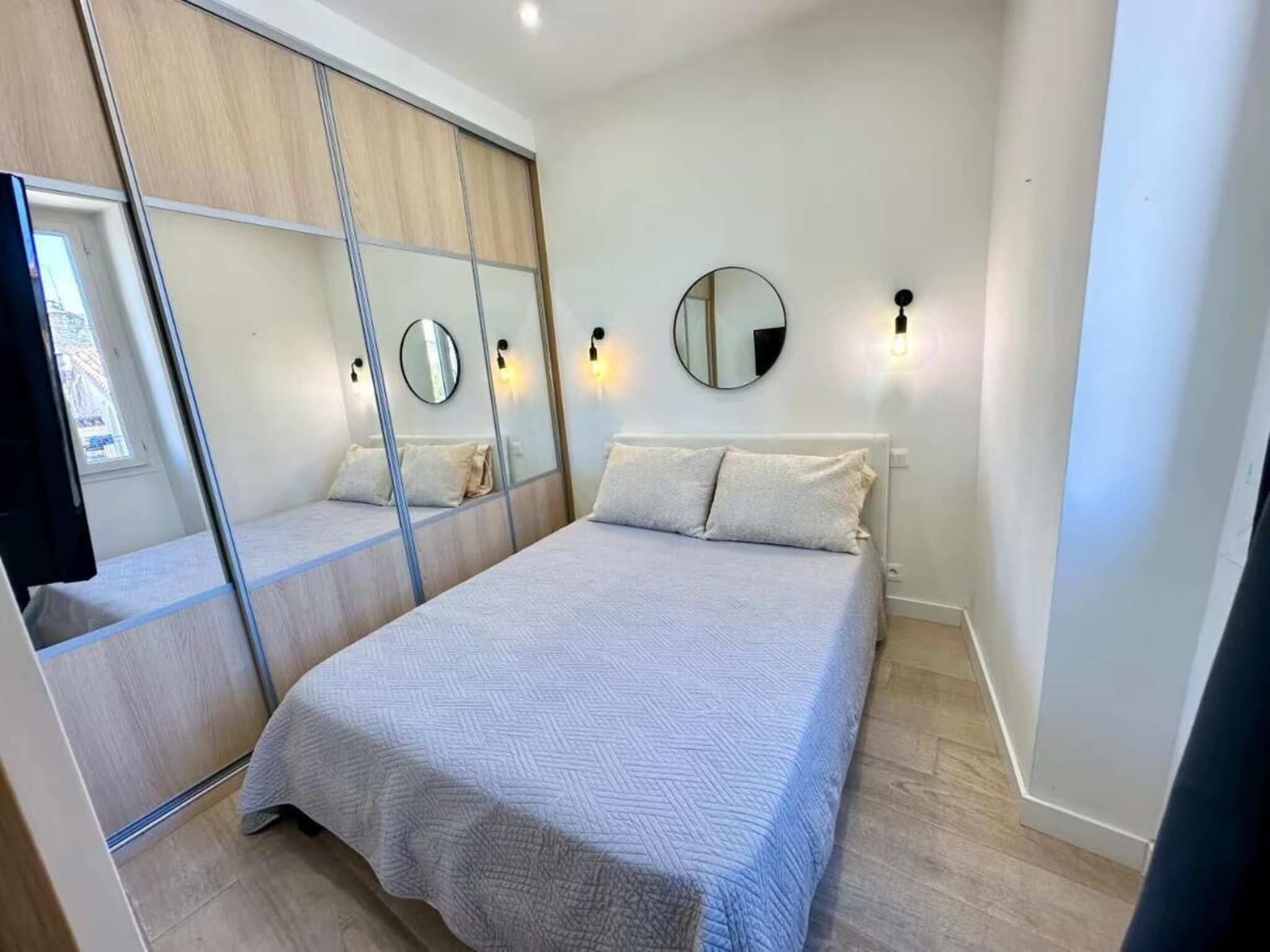 Un dormitorio con cama, espejo y armario.