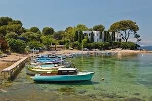 A marina with boats docked, a wooden pier, and a building with trees in the background.
