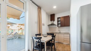 A compact kitchen with a dining area, a refrigerator, and a view of the outside balcony. - Lovely Studio With Seaview - Margarita (Ishëm)