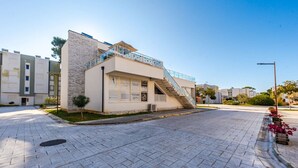A modern building with a staircase leading to a balcony, surrounded by a paved area and greenery. - Seaview Haven - Trendafili (Ishëm)