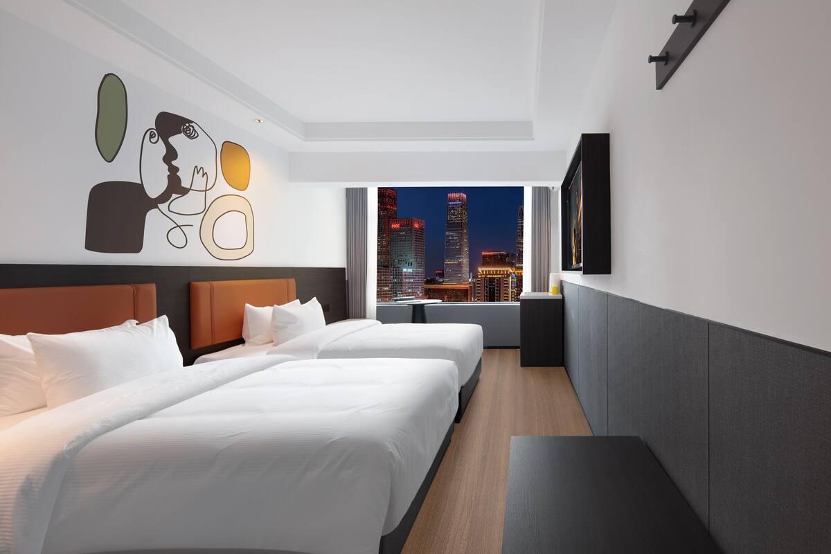 Een hotelkamer met twee bedden en uitzicht op een stadsbeeld, uitgevoerd in een modern design.
