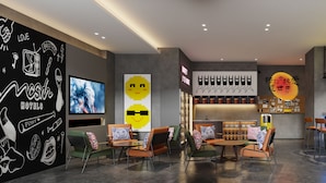 Un área de bar moderna con asientos, un televisor y un letrero de neón.