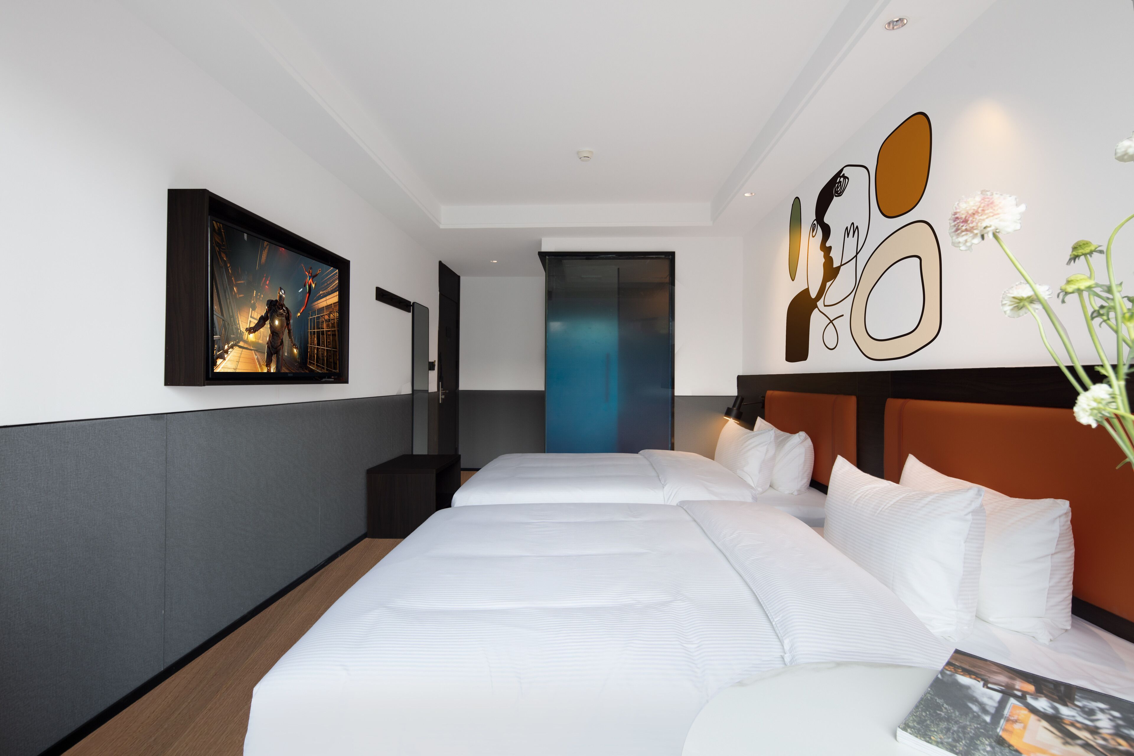 A hotel room with two beds, a large painting on the wall, a modern design with a blue accent wall, and a decorative wall piece.