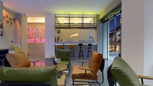 Un interior moderno con asientos verdes y marrones, un letrero de neón y una zona de bar.
