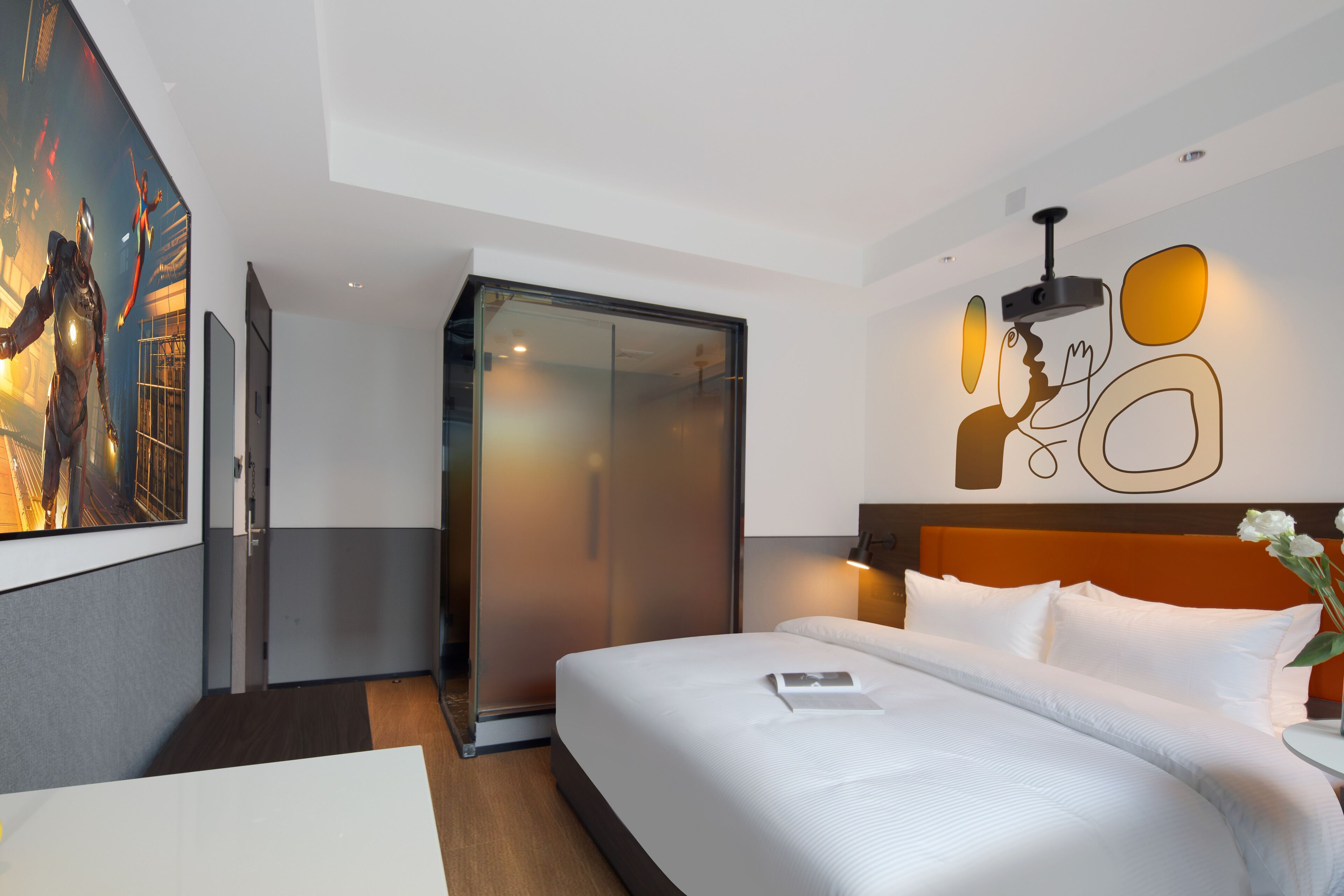 Une chambre d’hôtel moderne avec un grand lit, une armoire à portes vitrées et un mur orné d’œuvres d’art abstraites.