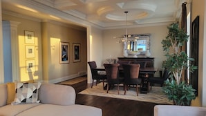 A spacious living room with a large sofa, a dining area with a table and chairs, and a decorative mirror above the table. - Sand and Salt Bed & Breakfast (White Rock)