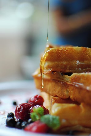 Close-up van een ontbijt bord met French toast, siroop en bessen.