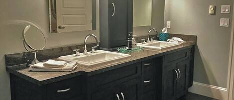 A bathroom with two sinks, dark cabinets, a mirror, and a towel rack.