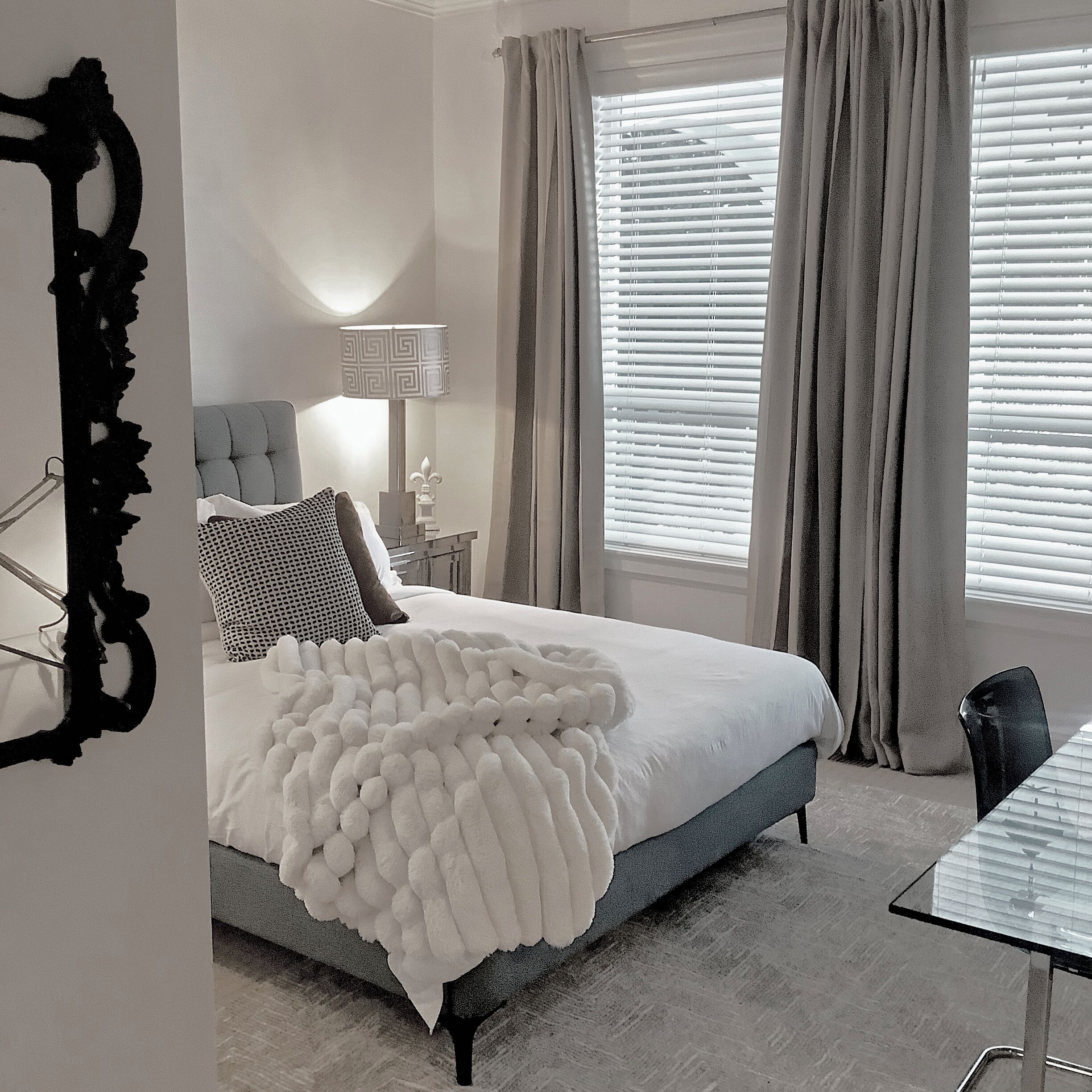 A bedroom with a bed, a chair, a lamp, and a window with curtains.