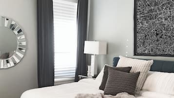 Een slaapkamer met een bed, een ronde spiegel, een lamp en een stadsgezicht op de muur.