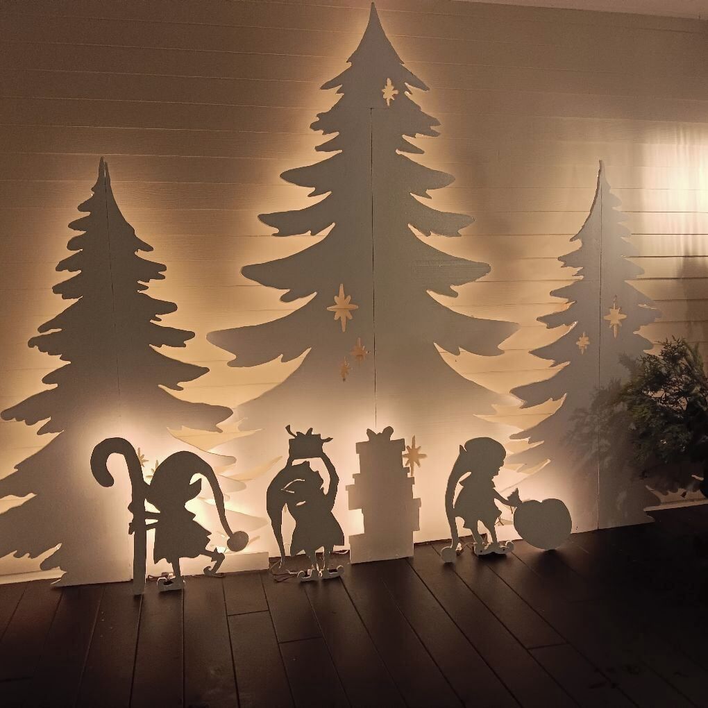 A room with a wooden floor, a wall with a cut-out Christmas tree design, and silhouettes of a cat, a dog, and a bird.