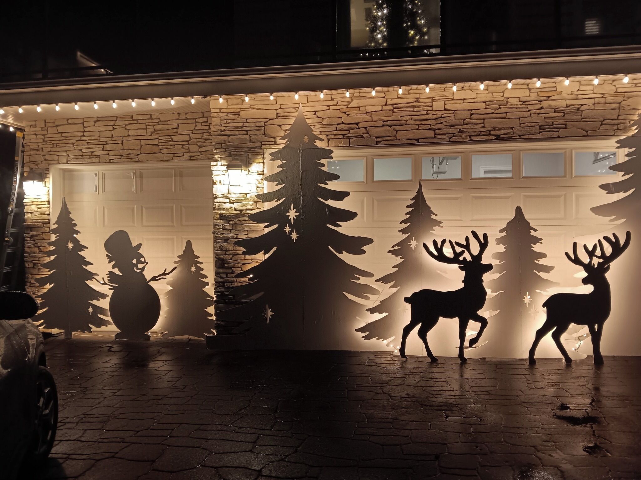 A garage with a stone facade and a Christmas tree silhouette decoration.