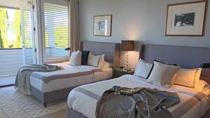 A hotel room with two beds, a large window with blinds, a lamp, and framed artwork on the walls. - Sand and Salt Bed & Breakfast (White Rock)