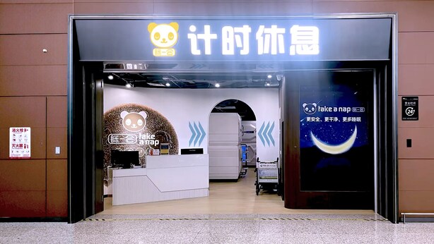 L’entrée d’un hôtel avec un comptoir d’accueil, un grand logo représentant un panda et un panneau indiquant « Faites une sieste ».