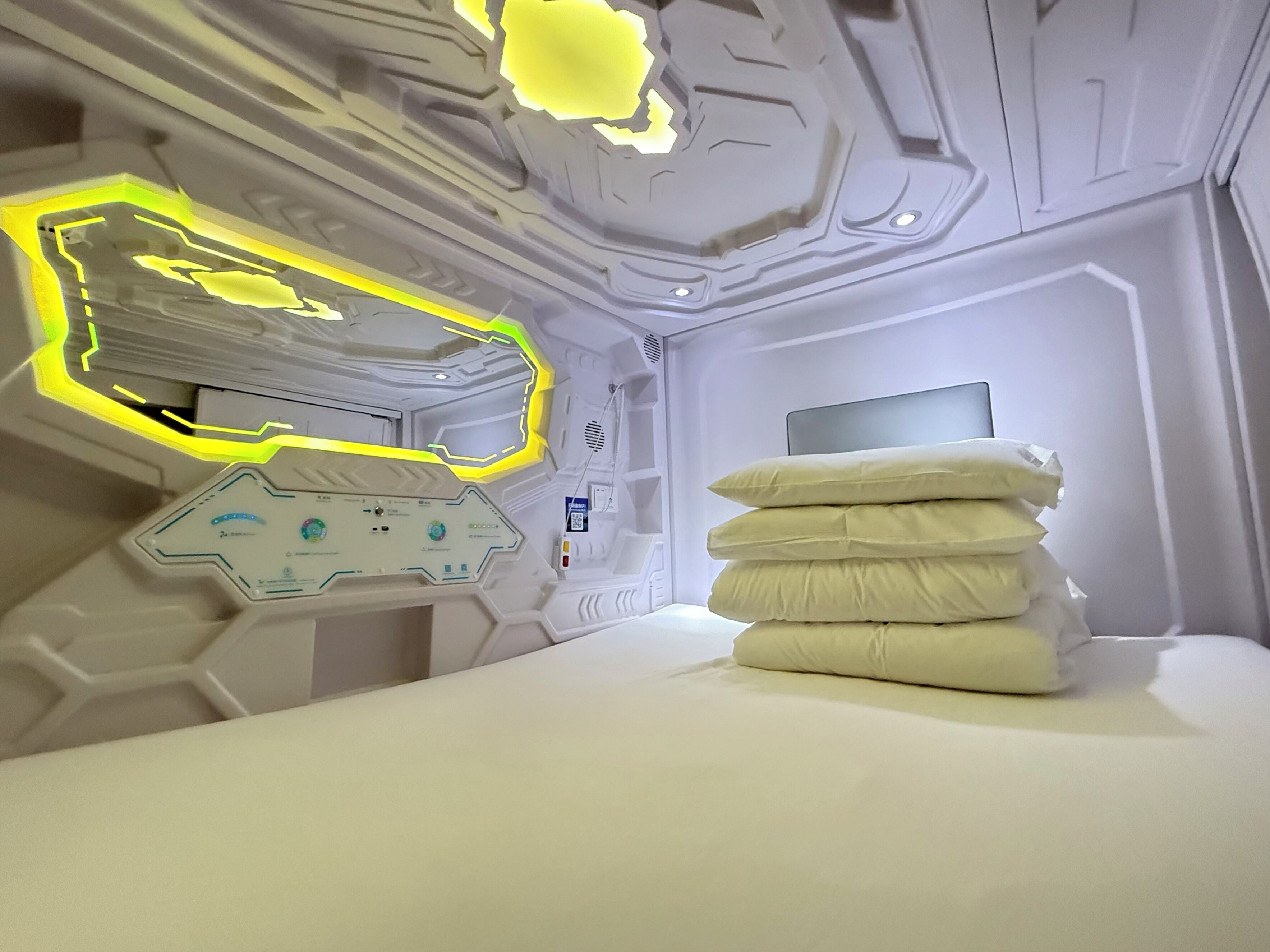 Um quarto futurista com uma cama, um painel de controle e um monitor.