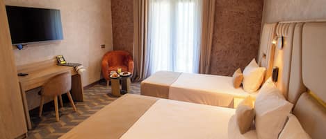 A hotel room with two beds, a desk, a chair, a TV, and a window with curtains.