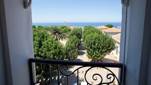 Un balcón con vista a un pueblo costero, árboles y un faro.