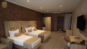 Habitación de hotel con dos camas, un escritorio, una silla, un televisor y un armario.