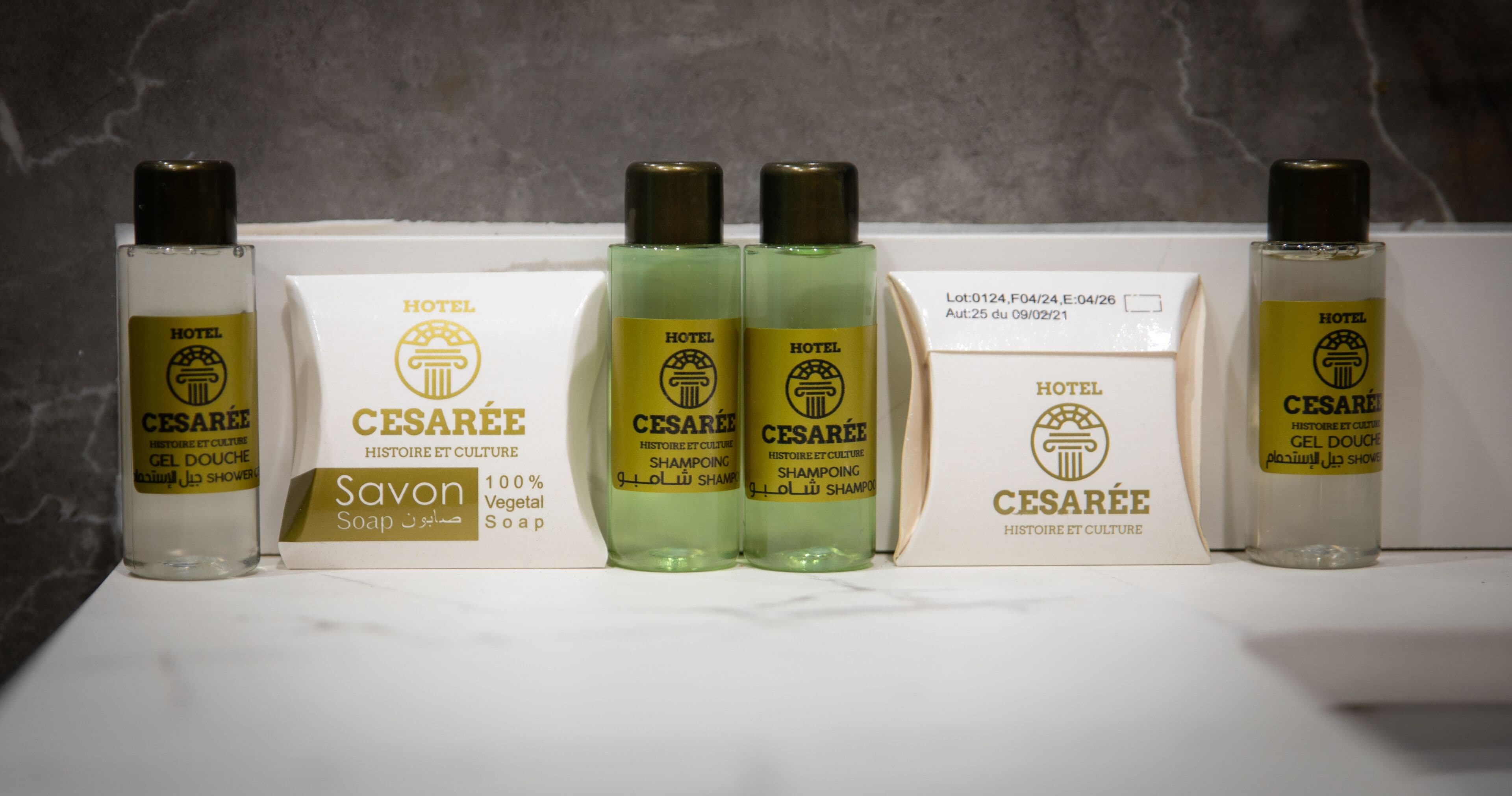 Une salle de bain d’hôtel équipée de divers produits de toilette, notamment un flacon de savon, deux flacons de shampoing et un flacon de gel douche.