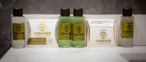 Une salle de bain d’hôtel équipée de divers produits de toilette, notamment un flacon de savon, deux flacons de shampoing et un flacon de gel douche.