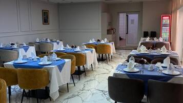 Une salle à manger avec des tables dressées pour le service, une fresque murale au plafond et un sol en marbre.
