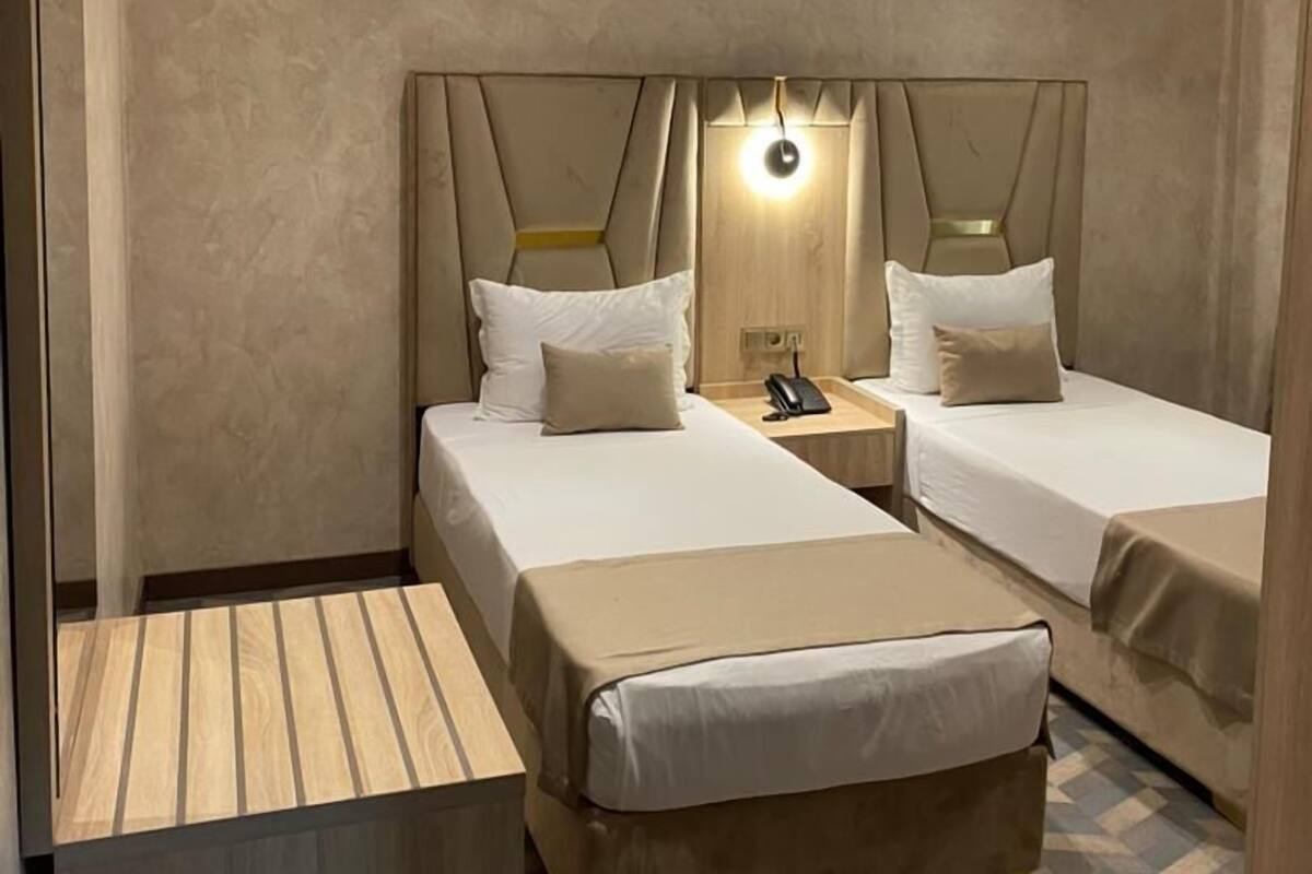 A hotel room with two beds, a wooden desk, and a patterned floor.