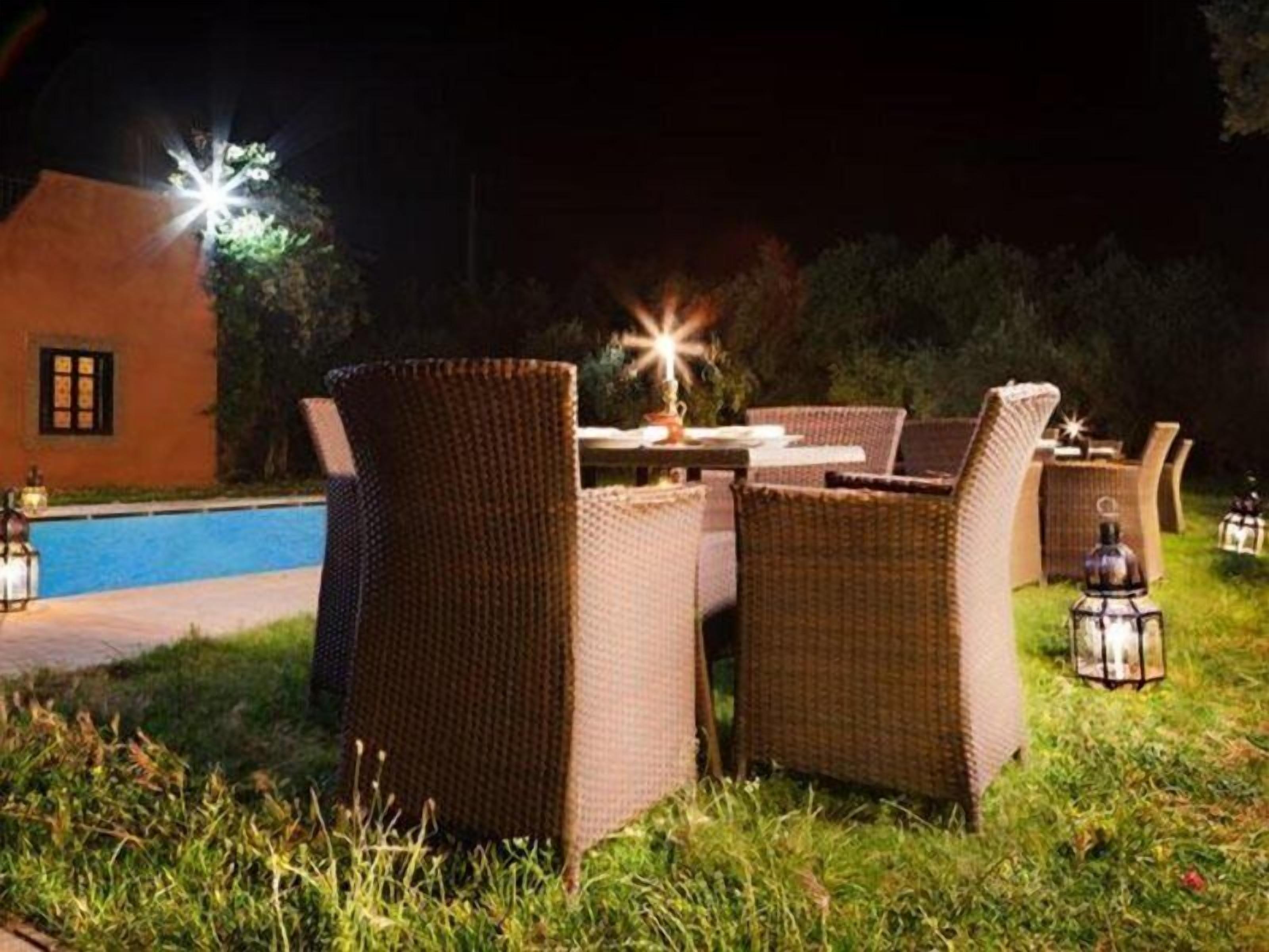 An outdoor dining area with wicker furniture and a pool in the background.