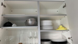A kitchen cabinet with shelves containing various kitchenware, including bowls, plates, and glasses. - Beautiful apartment in Rüschlikon Zurich (Rüschlikon)
