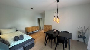 A modern bedroom with a bed, a small dining table, and a hanging light fixture. - Beautiful apartment in Rüschlikon Zurich (Rüschlikon)