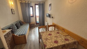 A compact room with a bed, a small table, a bench, and a dresser. - Ski studio at the foot of the slopes Valfréjus ski resort (Valfréjus)