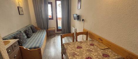 Una habitación pequeña con cama, una mesita, un banco y un aparador.