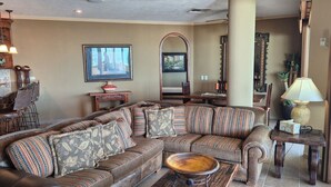 Ein Wohnzimmer mit einer großen Eckcouch, einem Couchtisch und einem Essbereich mit Tisch und Stühlen.