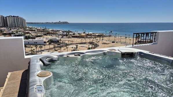 A hot tub with a view of the beach and ocean.