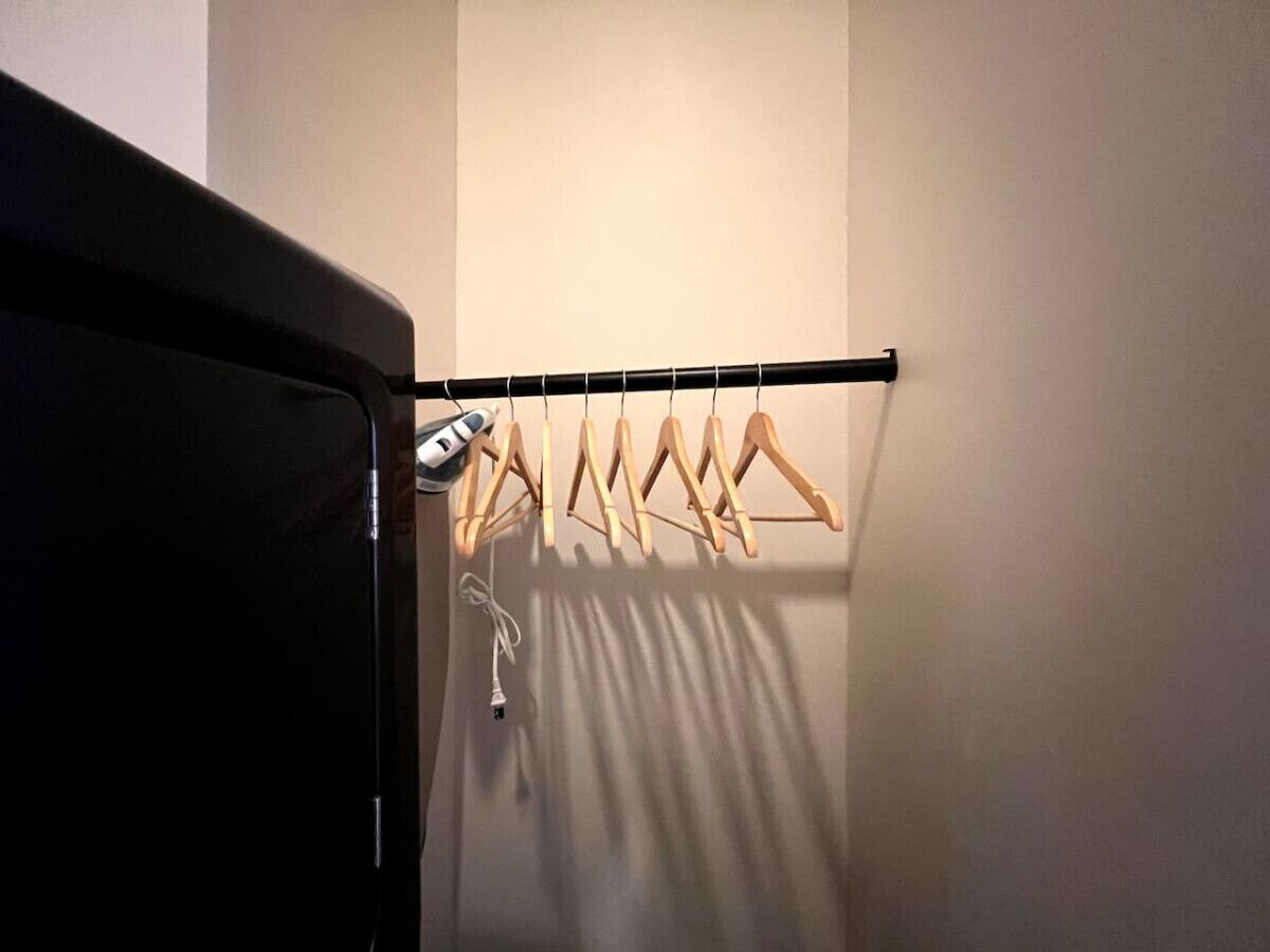 Ein Kleiderschrank mit Holz-Kleiderbügeln und aufgehängter Kleidung.